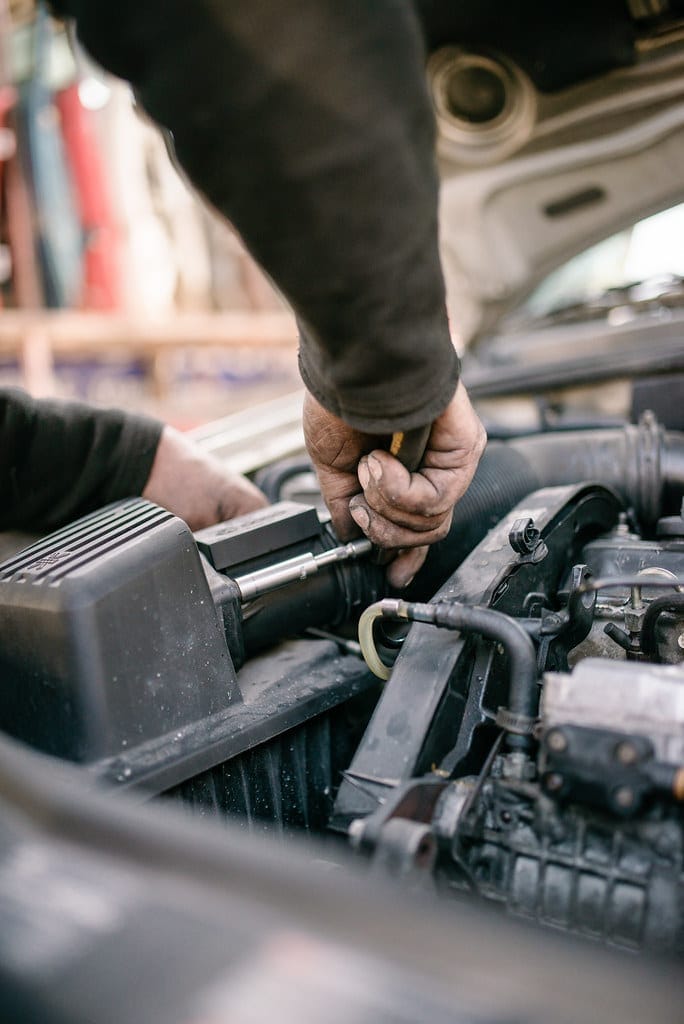 Szerelő kezei dolgoznak egy személyautó motorján a műhelyben